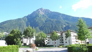 A residential area with a mountain in the background, featuring multi-story buildings with balconies and a clear sky. - Modern, new 3.5-room apartment in brig with fantastic views of the mountains (Brig-Glis)
