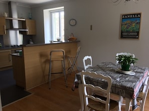 Kompakti keittiö, jossa on ruokailutila, ikkuna ja ZANELLAn juliste seinällä.