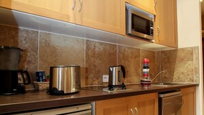 A modern kitchen with wooden cabinets, stainless steel appliances, and a tiled backsplash. - APARTMENT THE THREE FOUNTAINS (Sarlat-La-Canéda)
