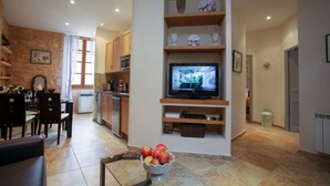 A modern living room with a TV, a dining area, and a kitchen. - APARTMENT THE THREE FOUNTAINS (Sarlat-La-Canéda)
