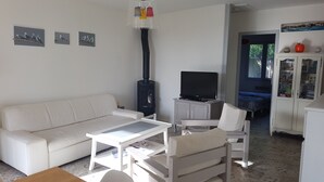 Un salon avec un canapé blanc, une table basse, un téléviseur posé sur un meuble et une cheminée.