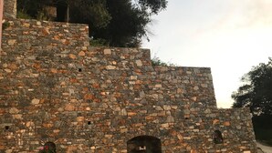 Un muro de piedra con una pequeña ventana de arco y una ventana rectangular con flores.