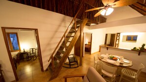 A dining area with a wooden staircase, a round table set for four, and a ceiling fan. - A third world oasis on the idyllic beach of Santa Clara. (Santa Clara)