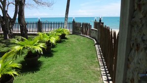A well-maintained garden with a curved fence, palm trees, and a view of the sea. - A third world oasis on the idyllic beach of Santa Clara. (Santa Clara)