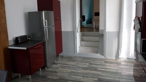 Eine kompakte Küche mit Kühlschrank, einer kleinen Arbeitsplatte und einer Treppe, die zu einer oberen Ebene führt.