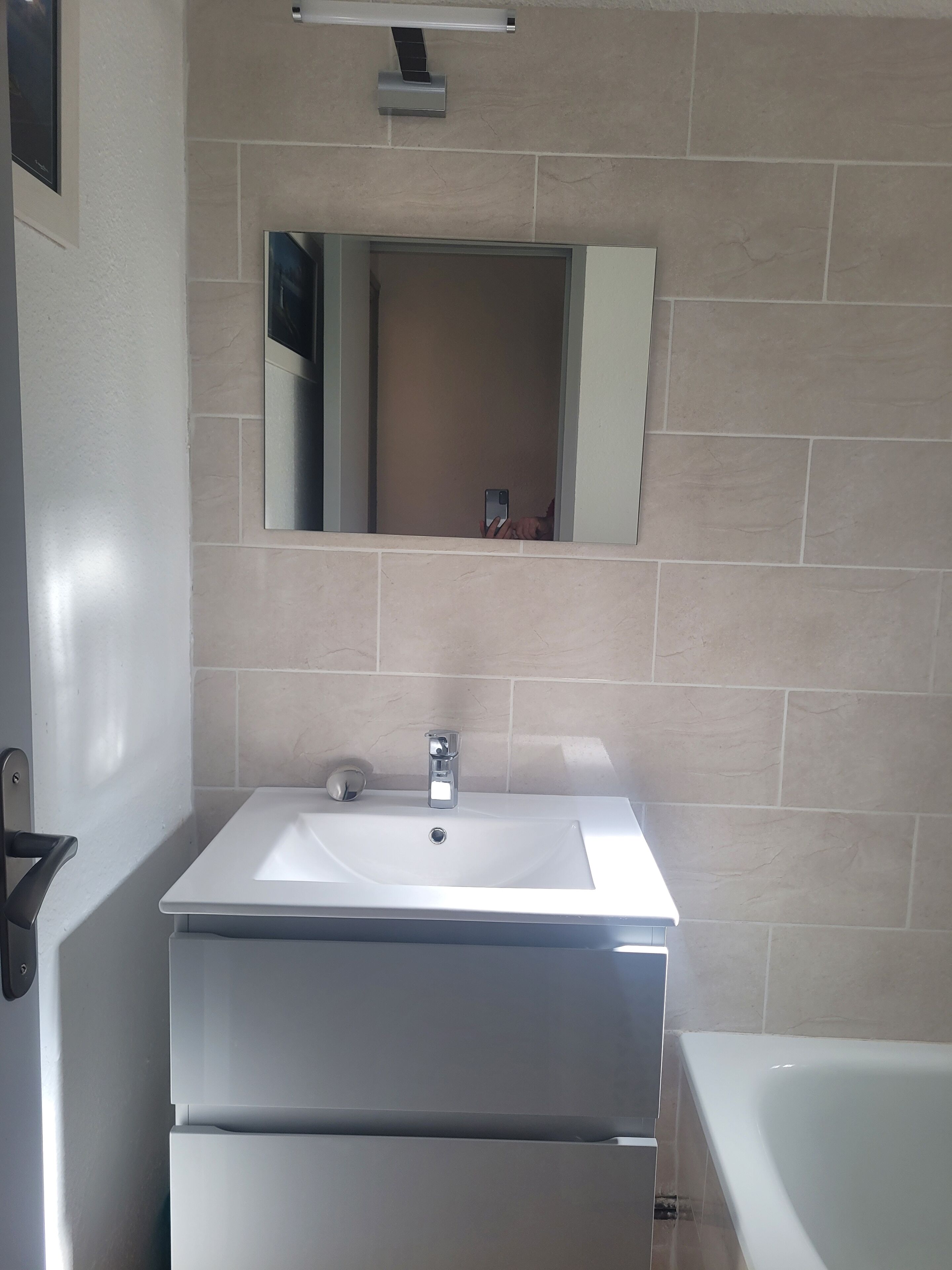 Une salle de bain avec un lavabo blanc, un miroir et une baignoire.