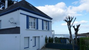 A white building with blue trim and a door, located near a body of water.