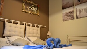 A neatly made bed with a white headboard, a blue towel, and a framed picture on the wall. - Apartment Sea View Balcony & Shared Pool Air Conditioning (Hyères)