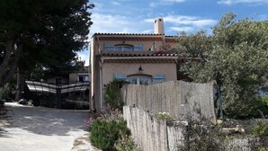A traditional Mediterranean-style building with a tiled roof, a stone chimney, and a wooden fence. - Apartment Sea View Balcony & Shared Pool Air Conditioning (Hyères)