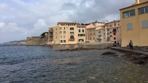 Ein Gebäude an der Küste mit mehreren Stockwerken, einer Steinsäule und freiem Blick aufs Meer.