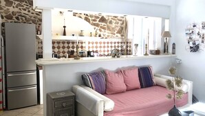 Eine kompakte Küche mit Steinrückwand, weißer Arbeitsplatte und eingebautem Backofen.
