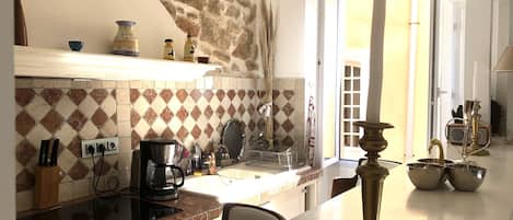 Une cuisine avec un mur en pierre, une machine à café et un évier.