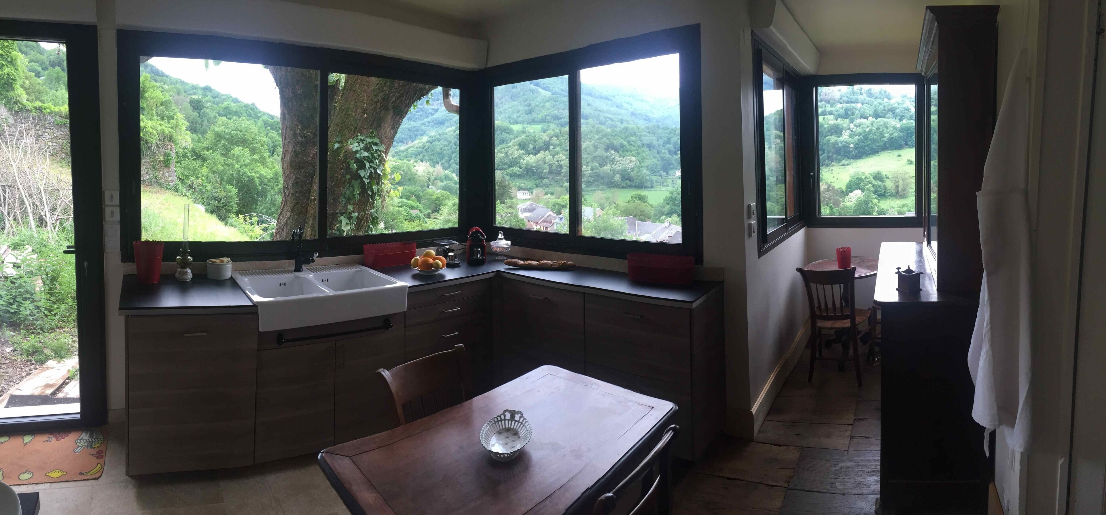 A kitchen with a large island, a sink, and a view of a green landscape through the windows.
