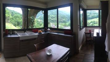A kitchen with a large island, a sink, and a view of a green landscape through the windows.