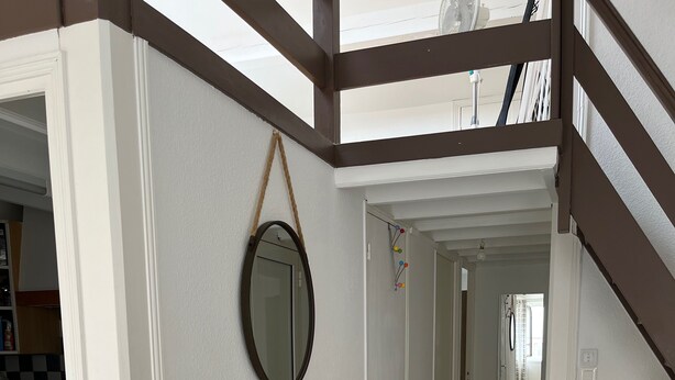 A hallway with white walls, a tiled floor, and a staircase with brown accents.