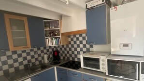 A compact kitchen with blue cabinets, a microwave, a coffee maker, and a refrigerator.