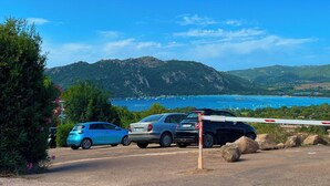 Une route côtière bordée de voitures garées et d’une barrière.