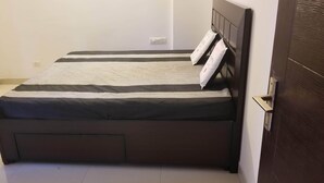 A small, neatly made bed with a dark headboard and a striped bedspread. - The most homely place in Noida (Sector 137)