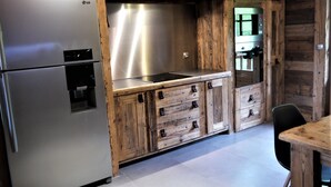 A kitchen with a stainless steel refrigerator, wooden cabinets, and a built-in stove. - Exceptional "Frachette" Chalet (Praz-Sur-Arly)
