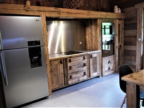 Una cocina con refrigerador de acero inoxidable, armarios de madera y estufa integrada.