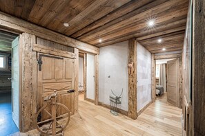 A rustic interior with wooden walls, a large wooden door, and a wheel mechanism.
