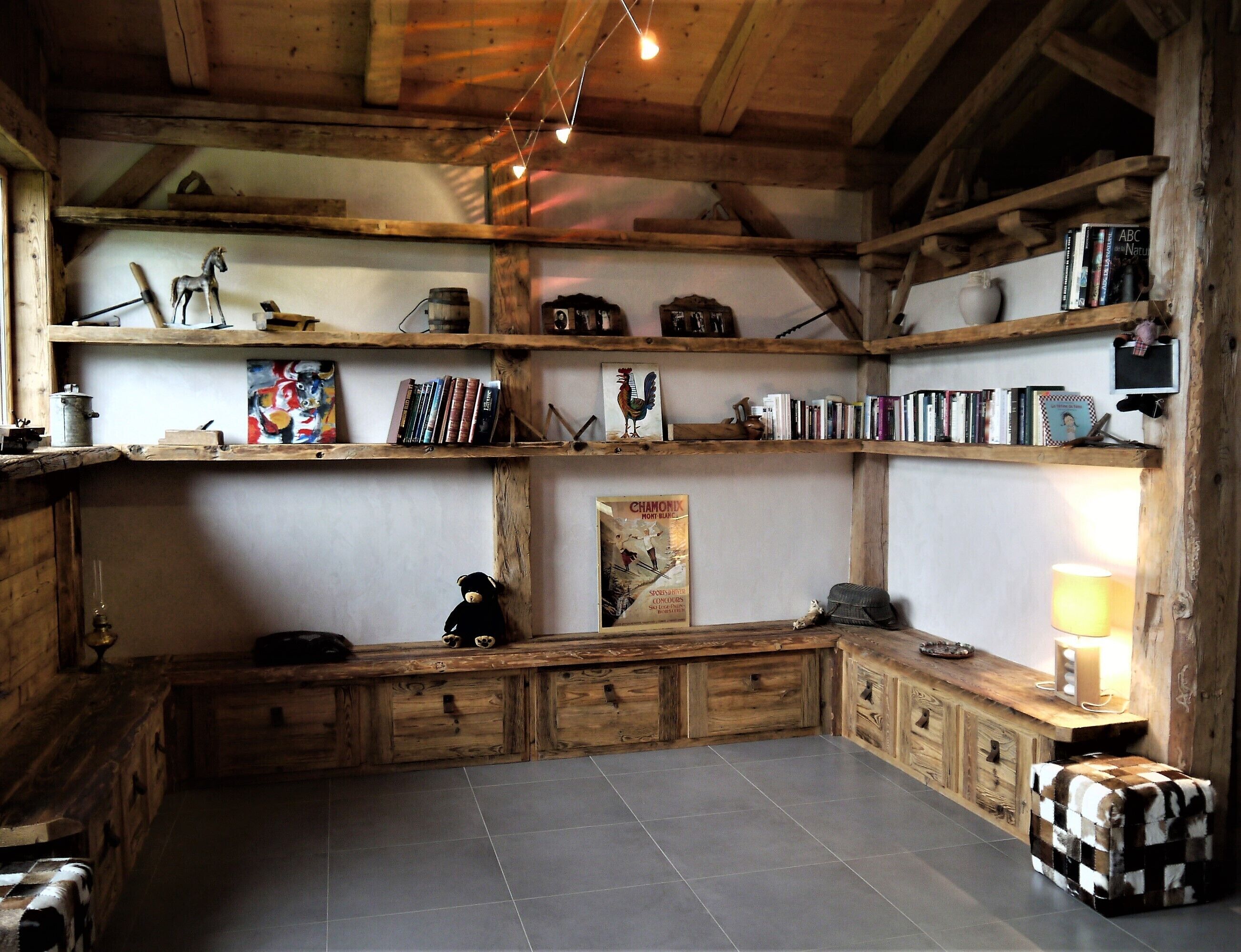 Una habitació rústica amb prestatgeries de fusta, una banca i un paviment de rajoles.