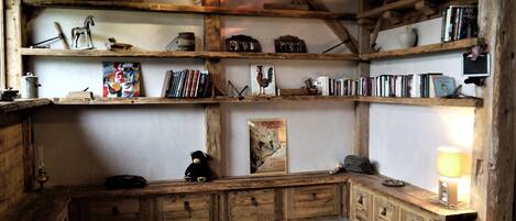 Una habitació rústica amb prestatgeries de fusta, una banca i un paviment de rajoles.