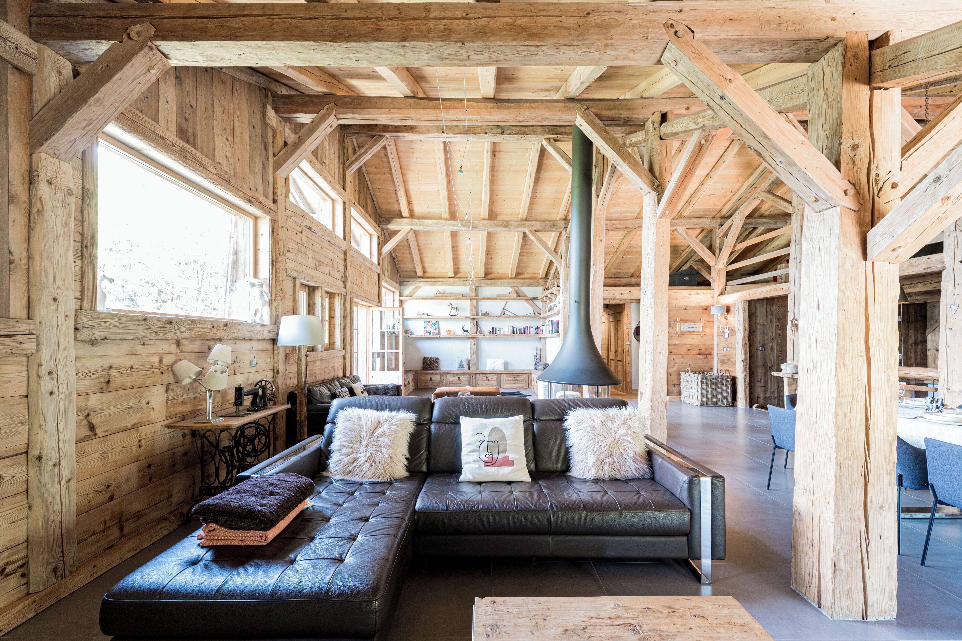 Un intérieur spacieux en bois, avec un grand canapé, un coin repas et une cuisine.