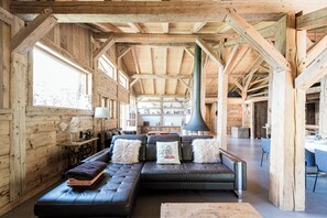 A spacious wooden interior with a large sofa, a dining area, and a kitchen. - Exceptional "Frachette" Chalet (Praz-Sur-Arly)