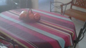 Ein Zimmer mit einem Bett, einem Fernseher, einem Esstisch mit Obst und einer Bank.