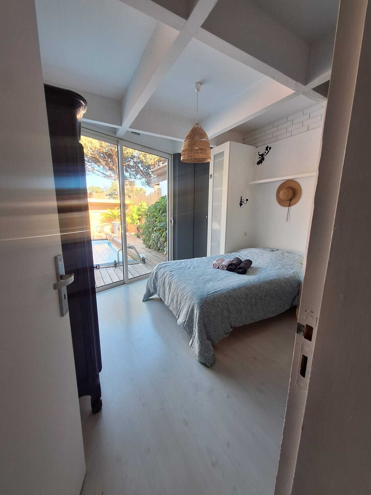 A bedroom with a bed, a door, a window, and a ceiling fan.