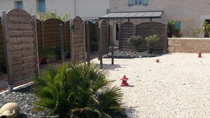 Une cour avec un sol de gravier, une clôture en bois et un hydrant rouge.