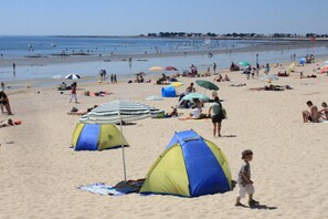 Una spiaggia con tende, ombrelloni e persone.