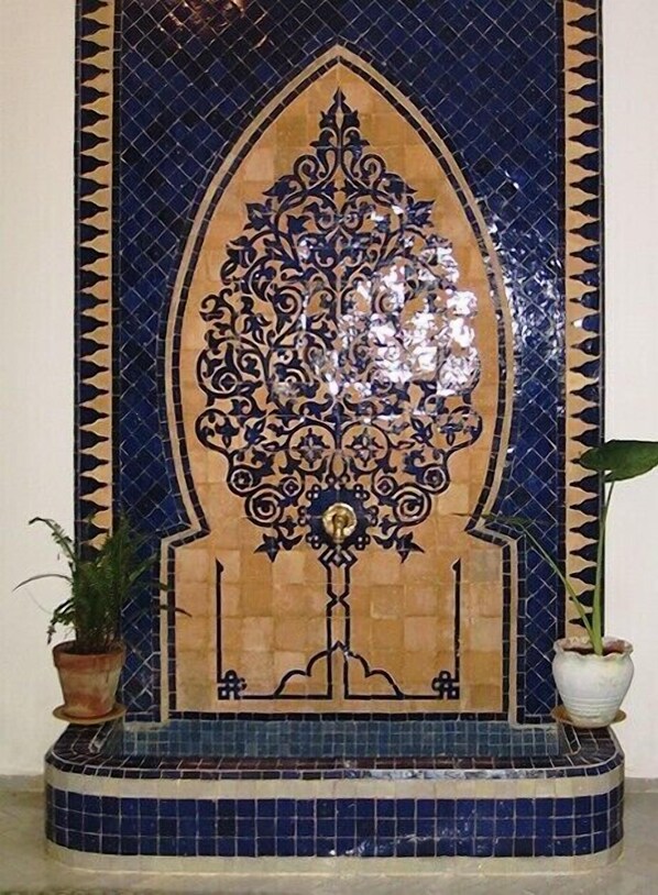A decorative tile wall with a central floral motif and geometric border. - Charming renovated house in the medina, beautiful sea view (Asilah)