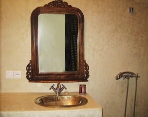 Une salle de bain avec un miroir à cadre en bois, un lavabo et une tasse à rayures rouges posée sur le comptoir.