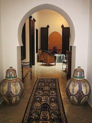 A hallway with an arched doorway leading to a dining area with a table and chairs. There are two decorative vases on either side of the hallway. - Charming renovated house in the medina, beautiful sea view (Asilah)