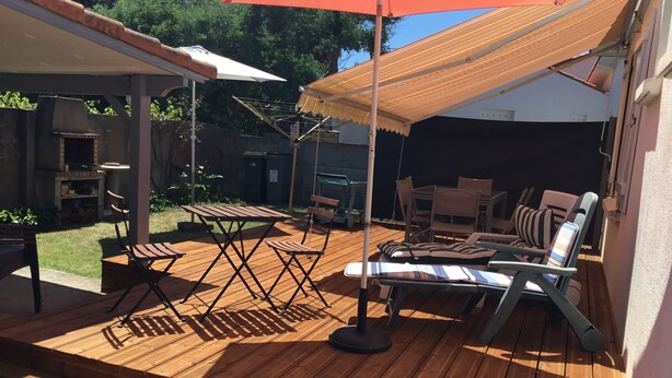 An outdoor patio with wooden flooring, a table, chairs, and a striped umbrella. - INDEPENDENT HOUSE CLOSE TO SEA AND PORT LA GRAVETTE 50 M (La Plaine-sur-Mer)