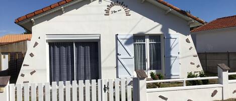A single-story building with a white facade, a red-tiled roof, and a white picket fence.