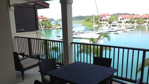 Uma varanda com mesa e cadeiras, com vista para uma marina com barcos e uma área de água.
