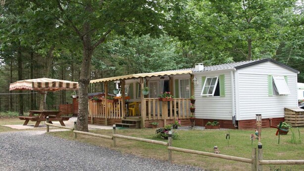 A small, single-story cabin with a porch, a picnic table, and a covered seating area. - Rental Neuvic Vallée Haute Dordogne (Neuvic)