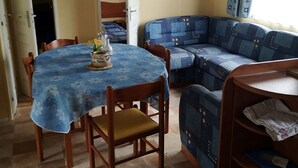 A cozy room with a dining table, a blue sofa, and a bed. - Rental Neuvic Vallée Haute Dordogne (Neuvic)