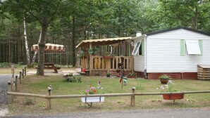 A mobile home with a porch, a picnic table, and a fenced yard with flowers. - Rental Neuvic Vallée Haute Dordogne (Neuvic)