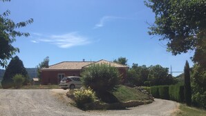 Un camí de grava que condueix a una casa vermella amb teulada de rajola.