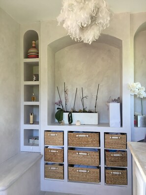 Um quarto com um nicho branco em arco, prateleiras com objetos decorativos e cestos de vime.