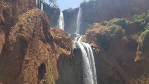 Una cascada en varios niveles que se precipita por un acantilado rocoso con poca vegetación.