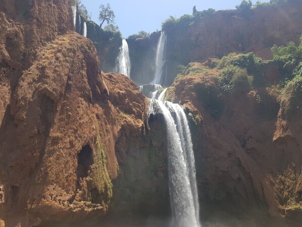 A multi-tiered waterfall cascading down a rocky cliff with sparse vegetation.