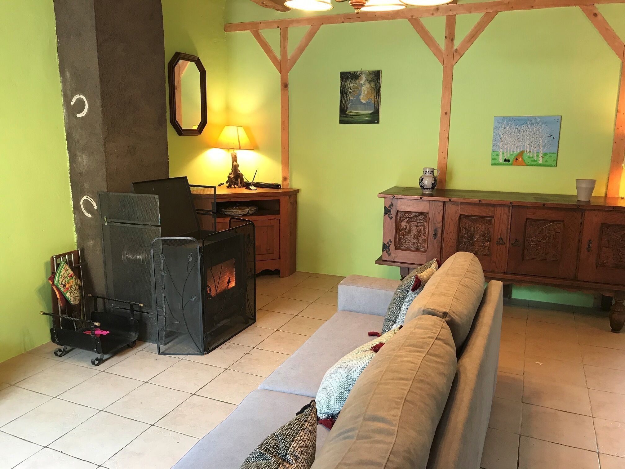 A cozy living room with a fireplace, a sofa, a wooden cabinet, and a lamp.