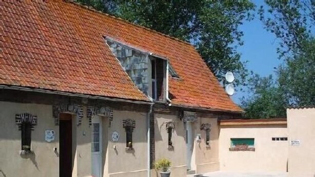 Un bâtiment doté d’un toit rouge à pente, de nombreuses fenêtres et d’antennes paraboliques.