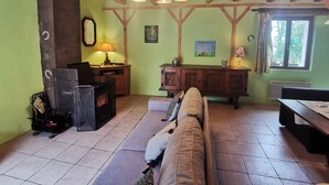 Un salon chaleureux avec un plafond en bois, un canapé, une cheminée et une fenêtre avec des rideaux.