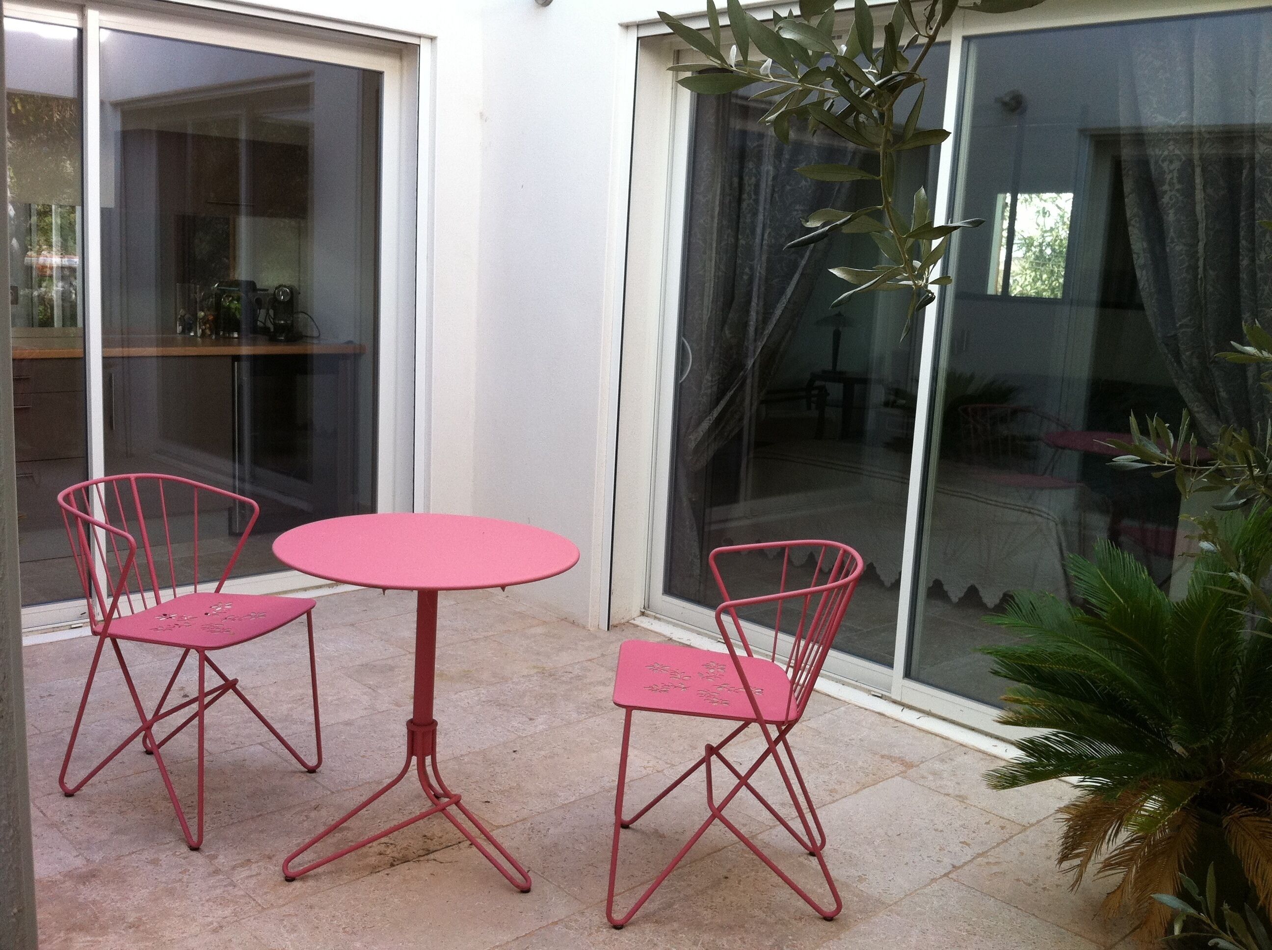 A glass door leading to a patio with a round table and two chairs.